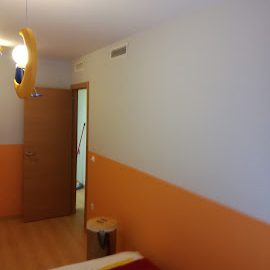 Hombre pintando una pared de color amarillo con rodillo.